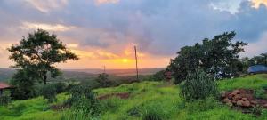 a sunset over a field with a car on a hill at Fulora Guesthouse in Dapoli