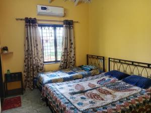a bedroom with two beds and a window at Fulora Guesthouse in Dapoli