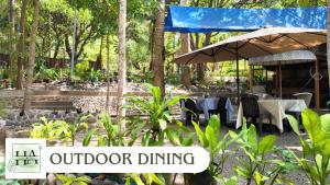 an outdoor dining area with an umbrella and tables and chairs at Hangin at Agos Resort in Nasugbu