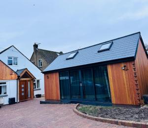 a wooden house with glass doors on a courtyard at Golden Oak Guest House in North Leigh