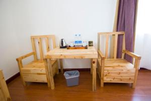 une table en bois avec deux chaises et une table avec un téléphone dans l'établissement Han Shu Xiang Yuan Hostel, à Jianshui