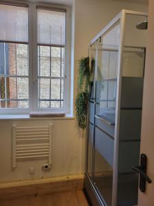 a glass shower in a room with two windows at studio Anémos in Fécamp