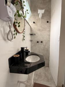 a bathroom with a sink in a black counter at Pousada Minas Gerais in Araxá
