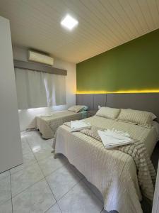 a bedroom with two beds and a green wall at Loft J&C 01 in Primavera do Leste