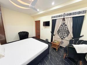 a bedroom with a bed and a chair and a television at Serene Elegance Hotel in Islamabad