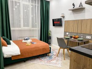 a bedroom with a bed and a desk and a kitchen at Contento Apartments in Almaty +20 photos