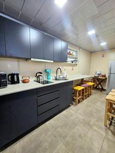 a large kitchen with black cabinets and a table at Green Owl in Dedoplis Tskaro