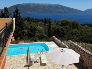 a swimming pool with an umbrella and a view of the water at Sea View Villa Irene - Private Pool and Sunset Terrace in Evretí