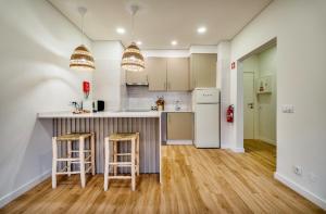 a kitchen with a counter and two bar stools at Brisa do Mar in Quarteira
