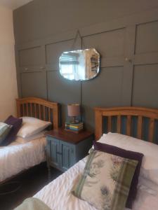a bedroom with two beds and a table with a lamp at The Mews, Talley in Llandeilo