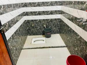 a toilet in the floor of a building with a bucket at The rest point dormitory in Khātu