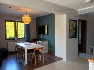 a kitchen and dining room with a table and chairs at Dom Mazurska Apartamenty in Rydzewo