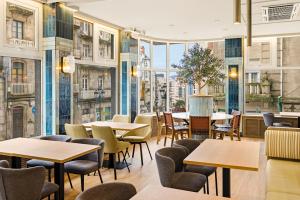 a restaurant with tables and chairs and large windows at B&B HOTEL Vigo in Vigo