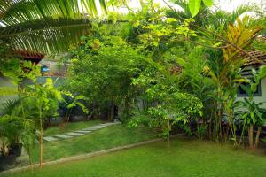 a garden with trees and plants in front of a building at Muraaya in Habaraduwa Central +12 photos