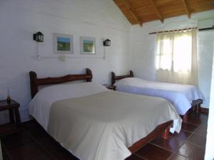 two beds in a room with white sheets at Iberá Porá in Colonia Carlos Pellegrini