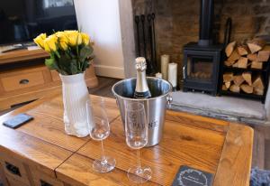 a table with a bottle of champagne in a bucket and two wine glasses at Wallnook Cottage Luxury Yorkshire Escape in Lindley
