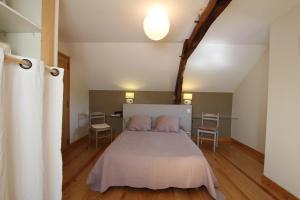 a bedroom with a bed and two chairs at Chez soule in Riupeyrous