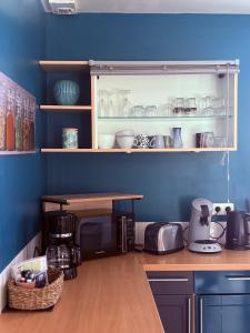 a kitchen with blue walls and a counter with a table at Aux Portes de La Roussille in Niort