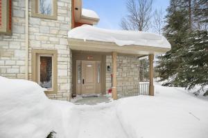 a building with a door covered in snow at House On The Golf La Bte -10min To Tremblant 150 in Mont-Tremblant