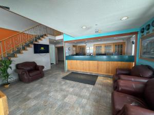 a living room with two chairs and a staircase at Howard Johnson by Wyndham Fort St. John in Fort Saint John