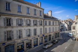 a city street with cars parked in front of buildings at Le Millésime in Dijon