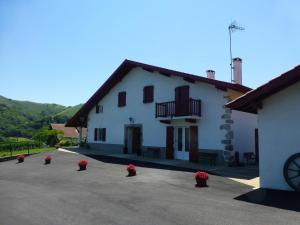 a white building with red flowers in a parking lot at Aguerrea in Macaye