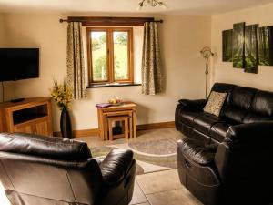 a living room with two leather couches and a television at Tyn Y Celyn Canol in Clocaenog