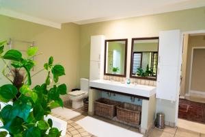 a bathroom with a sink and a toilet and a mirror at Shepherd's Corner Guest House - Tranquil Boutique Stay in Bryanston in Johannesburg +106 photos