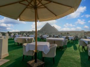 a group of tables and chairs under an umbrella at Sahary Pyramids View Hotel in Giza