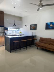 a kitchen with a bar with stools and a couch at LOFT 3 Tulum in Mexicali