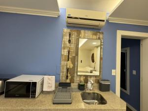 a kitchen with a microwave and a sink and a mirror at Suite Juede Platz - 02 - Centro de Pomerode in Pomerode +18 photos