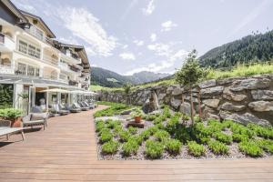 a hotel with a stone wall and a patio at Traumhotel Alpina - 4 Sterne Superior Luxushotel, hoteleigenen Badesee, Adults Only in Gerlos