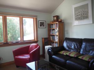 a living room with a black leather couch and a red chair at Captain Eady's Lookout in Portobello