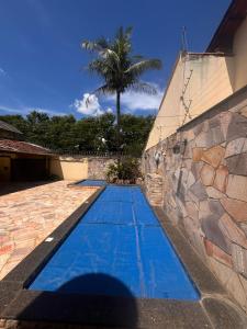 a swimming pool next to a stone wall with a palm tree at Pousada Gaivota in Trindade