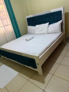 a bed with a blue headboard and white sheets and pillows at The O,S Homestay in Chuka