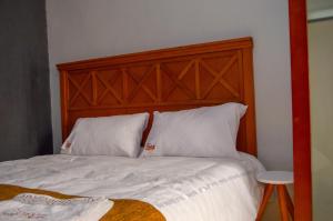 a bed with white pillows and a wooden headboard at Fusion Apartments in Lusaka