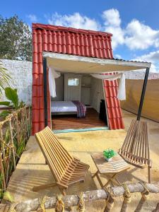 a bed and two chairs in a red house at Las siete lunas in Ucú