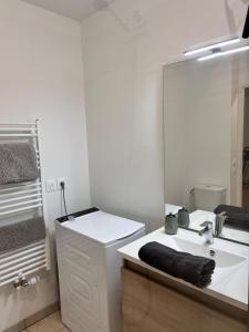 a white bathroom with a sink and a mirror at T2 Cosy avec Terrasse & 2 parkings privés in Saint-André-de-Cubzac +19 photos