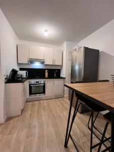 a kitchen with white cabinets and a wooden table at T2 Cosy avec Terrasse & 2 parkings privés in Saint-André-de-Cubzac