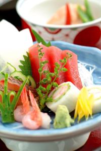un plato azul de comida con sushi y verduras en Hotel Kinomezaka, en Minami Uonuma