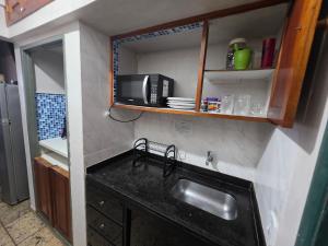 a kitchen with a sink and a microwave at PERÓ BEIRA MAR - Flat âncora - 203A in Cabo Frio +15 photos
