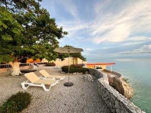 a patio with two chairs and an umbrella next to the water at Sun Reef Village on Sea in Willemstad