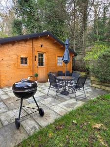 a grill and chairs and a table and a cabin at Secluded Log Cabin escape in High Wycombe