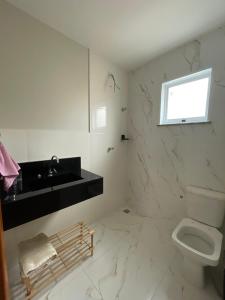 a white bathroom with a sink and a toilet at Apartamento em Poços - Varanda com Churrasqueira in Poços de Caldas +17 photos