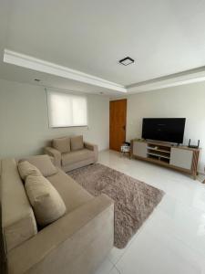 a living room with a couch and a flat screen tv at Apartamento em Poços - Varanda com Churrasqueira in Poços de Caldas