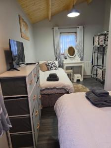 a bedroom with two beds and a dresser with a television at Secluded Log Cabin escape in High Wycombe