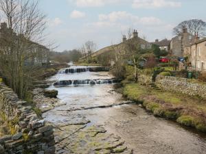 a river in a town with a waterfall at Hillside View in Hawes