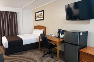 a hotel room with a bed and a desk and a television at Northern Lights Inn & Suites in Valleyview