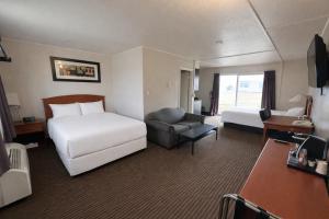 a hotel room with a bedroom with a bed and a chair at Northern Lights Inn & Suites in Valleyview