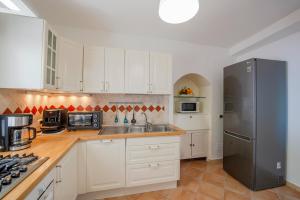 a kitchen with white cabinets and a black refrigerator at Oasi Milano in Furore